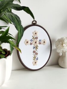 Owalny obrazek z haftowanym krzyżem i kwiatami