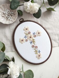 Owalny obrazek z haftowanym krzyżem i kwiatami