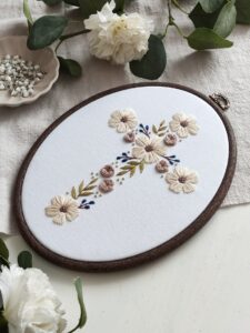 Owalny obrazek z haftowanym krzyżem i kwiatami