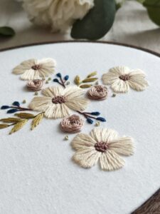 Owalny obrazek z haftowanym krzyżem i kwiatami