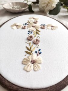 Owalny obrazek z haftowanym krzyżem i kwiatami