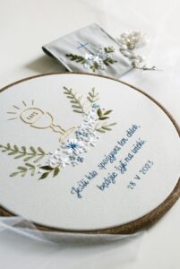 Haftowana pamiątka Pierwszej Komunii Świętej z cytatem, motyw kielicha z hostią i kwiatami