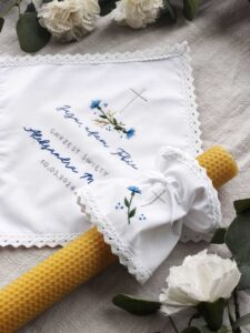 Biała szatka na chrzest z profitką i świecą. Zdobione ręcznie motywem chabrów.