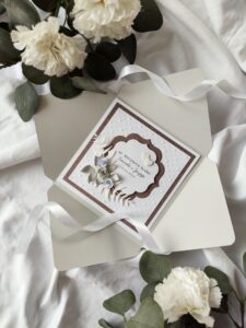 Elegancka kartka na rocznicę ślubu z imionami jubilatów i papierowymi kwiatami oraz serduszkami