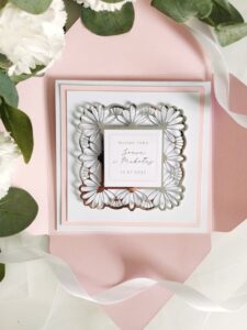 Pastelowo różowa kartka ze srebrną ażurową ramką i personalizacją na ślub